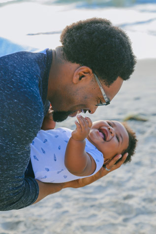 Father with baby on the beach laughing
