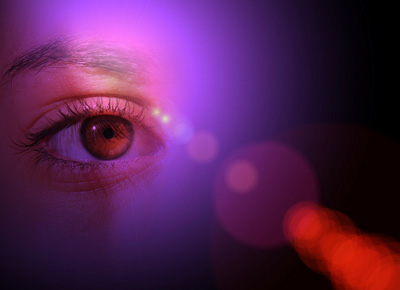 Image of a person’s eye looking out in purple and red light