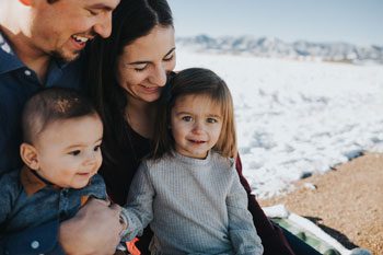 A mother, father, and two children smile for a photo at the beach