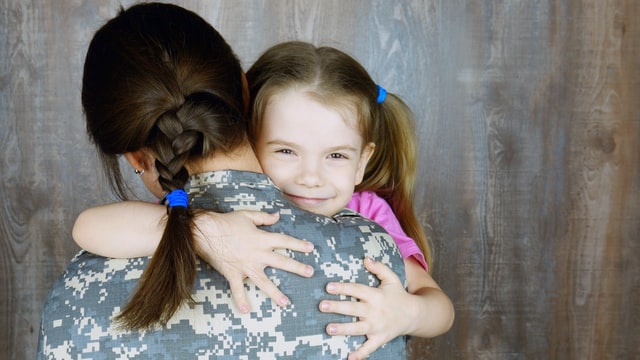Woman in military uniform hugging daughter