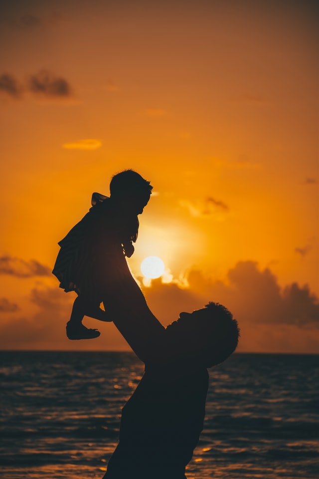 Silhouette of a parent with their child at sunset on the beach